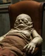 Placeholder: a chubby really old mummified corpse, eyes closed, leaned over in a brown chair