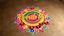 Placeholder: (front view of) Title Of the song "Rangilo Moh" written in abstract brush style font with golden color inside a colorful Rangoli on a earthy rustic floor-surface with six diya decorating the rangoli.