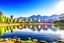 Placeholder: Sunny day, distant modern city, lake, lake reflections, people, mountains