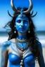 Placeholder: A photo of a blue skin Hindu goddess with painted blue face and body skin, wavy black hair deer antlers standing on a sunny beach