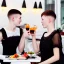 Placeholder: Russian guy young wife boyish boylike short man's haircut men's face boyish features in black girlish lacy cocktail dress as mother in restaurant