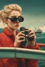 Placeholder: 23 years old girl, with blond hair and a messy bun. standing on in a red boat, wearing red clothes and looking trough binoculars watching something in the middle of the sea. You see the whole boat. You see the gril in front. It's a ferry. Wes anderson style. In front. Sarcastic