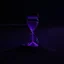 Placeholder: an hourglass on a beach at night, partly buried in the sand, dark purple light