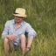 Placeholder: man with a panama hat reflects sitting in a meadow