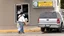 Placeholder: woman hands the bundles of cash her mobile phone provider's located across the street from an boarded up liquor store