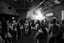 Placeholder: dans golv på en nedsliten sunkig techno club, många personer som dansar, yppiga lättklädda kvinnor, scen rök och ljus strobes, svartvit bild, en del personer ser in i kameran och skriker: "Benny!" och en Neon Skylt med texten "DJ ROY" på väggen