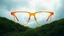 Placeholder: generate an image of large , square, orange glasses, in 3d style, standing in a hilly, green landscape with grass, and a morning mist. Its breathtaking. in the clouds. Use orange and dark blue as colors