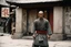 Placeholder: [very impressive high res masterpiece in Kodak Eastman 5247, bokeh scene by Stanley Kubrick] Ip Man Shaolin gangsta monk covered by tattoos waiting outside, on a stone doorstep, he menaces the camera