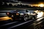 Placeholder: A mirror polished silver Lamborghini countach flies through a tight turn on a banked race track of pitch black tarmac leaving flaming tire tracks behind it as it breaks the sound barrier and produces a pressure cone before it and leaves a sonic boom behind it