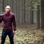 Placeholder: georges st pierre with a red plaid shirt a backpack and a riffle in a creepy forrest with zombies