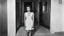 Placeholder: [photo by Russ Meyer] facing a woman on the door step of an appartement, in gym, talking. we see the corridor behind her