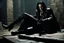 Placeholder: Action shot of Tom Hiddleston as Alucard from the live action "Hellsing" movie based on the anime of the same name. He is sitting, arms chained to a dungeon wall. He appears to be little more than a desiccated corpse wearing black wrappings that cover all except his head, feet, and hands. His straight, black hair hangs to the floor. A vague smile is on his gaunt face.