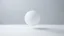 Placeholder: Create an image featuring a lone, pure geometric figure, like a smooth, white sphere, floating purposefully in an infinite, minimalist space. The background should be composed of a seamless, gradient transitioning from soft white to a very light grey, emphasizing the vast emptiness and the sense of infinity. The sphere should cast a subtle, soft shadow that gently fades into the background, enhancing the spatial depth and minimal aesthetic. The overall atmosphere should evoke tranquility, simpli