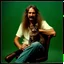 Placeholder: Awkward portrait Photo, 40 years old sitting on chair, weird smiling, long 1970 hippie hair and mustasch, bland polaroid camera, holding a cat