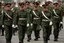 Placeholder: caucasian soldiers; marching in formation; military parade; tight formation; shoulder to shoulder; marching along a street; green uniforms; medals and insignia; weapons in hands;