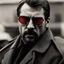 Placeholder: a young man with big muscles who looks like hans gruber wearing a heavy coat and red sunglasses staring with an angry look on his face