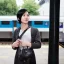 Placeholder: A beautiful slender Asian woman with short black hair waiting for a man at a train station in London