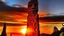 Placeholder: A wooden totem pole with carved faces against a vibrant sunset sky with a large sun set in a silhouetted landscape