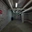 Placeholder: Photograph of a room museum, installation, cellar basement, brutalist, pipes, signs, empty, details of the walls very accentuated, liquid, noon-light