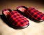 Placeholder: Red plaid slippers laying on a bearskin rug by log cabin hearth