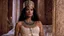 Placeholder: [Conan The Barbarian' (1982)] Nefertiti, the daughter of Pharaoh Ay, stirred from her slumber in the opulent palace. With a regal grace that spoke of her royal heritage, she rose from her bed and adorned herself in a sheer linen dress, the fabric whispering against her skin like a gentle breeze. Adorning herself with jewels that sparkled like stars in the morning light, Nefertiti made her way to the grand chariot that awaited her outside. With a bundle of sweet dates in hand, she stepped into th