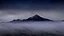 Placeholder: misty foreground and night sky, no sun, single mountain peak coming through the mist