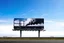 Placeholder: surreal full color photograph, long shot of a billboard on side of a highway containing a modern mural of giant smokestacks spewing thick dark billowy smoke that transgresses the billboard pouring into the real sky congealing into a cloud on the horizon, surreal, sophisticated, profound, dramatic