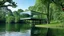 Placeholder: A modern, minimalist glass house is situated on a lake, surrounded by lush green trees. The house is a simple rectangular structure with large glass windows that reflect the surrounding landscape. The house is elevated on a platform, giving it the appearance of floating on the water. The lake is calm and still, with gentle ripples on the surface. The trees are tall and full, with a variety of shades of green. The sky is overcast, creating a soft, diffused light. The overall effect is one of peac