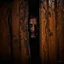 Placeholder: Close up of wooden door cracked open, in the crack an unsettling ghoulish decayed face stares back, horror photography by Joshua Hoffine, photorealistic, creepy, uneasy, eerie dark colors, heavy shadows