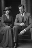 Placeholder: Up close Black and white photo of a serious couple sitting for portrait shoot in the 1920s