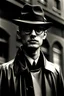 Placeholder: Polizeifoto schwarzweiß von 1965, neurasthenischer 30jähriger Mann in schwarzem Regenmantel mit Hornbrille und dunklem Hut, stechender Blick aus dunklen Augen, nervös
