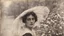 Placeholder: Vintage photograph of a woman in a hat with flowers, torn edges, cracks