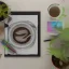 Placeholder: A High resolution photograph with soft lightning, of a a4 size drawing on a table next to two colored pencils. A green plant in a pot in the left top corner, a cup of coffee in the right top corner.