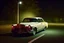 Placeholder: Coche Cadilac americano en mitad de la noche tan sólo iluminado por una farola y los faros del coche, imagen al estilo del fotógrafo Hugo Alonso